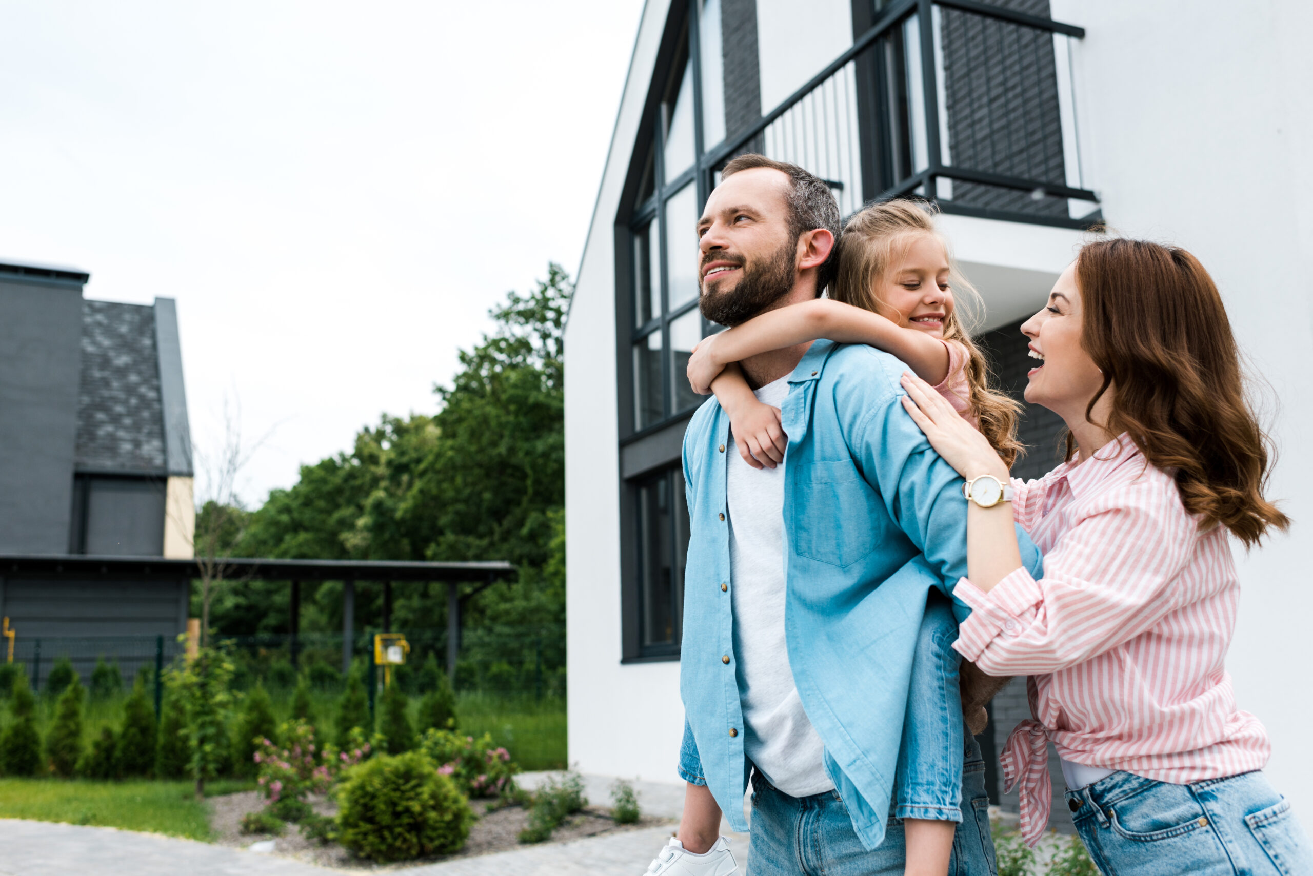Familie mit Kind vor ihrem Eigenheim