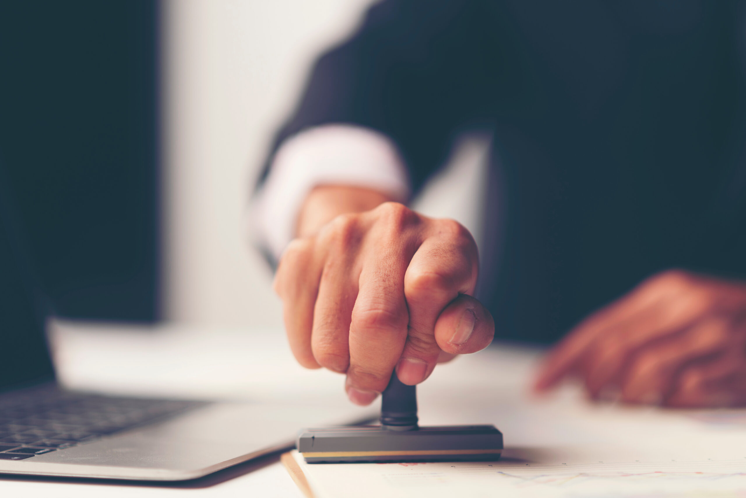 Hand stempelt ein Dokument am Schreibtisch – Thema Genehmigung
