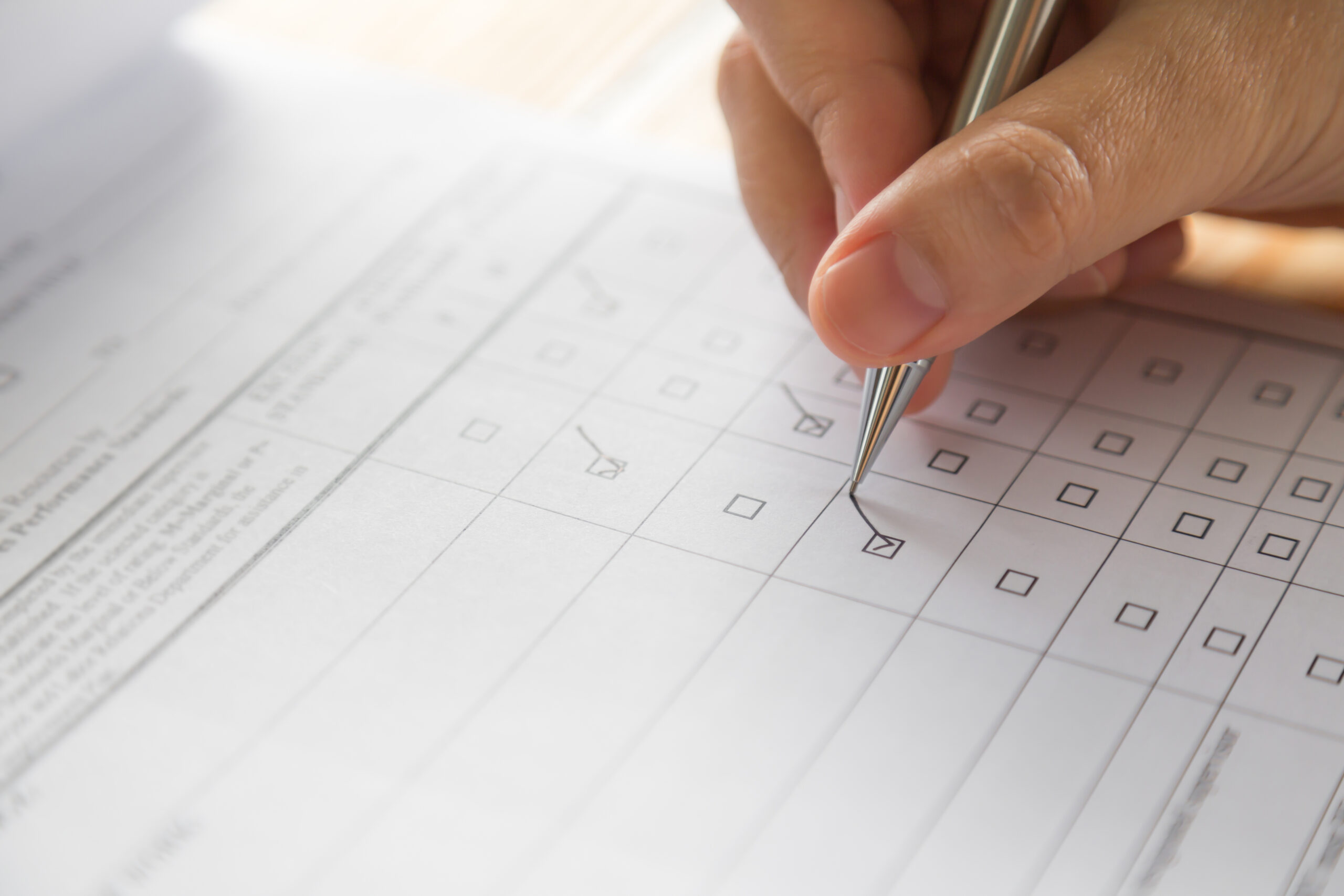 Hand füllt ein Formular mit Checkliste aus – Thema Bewerbung